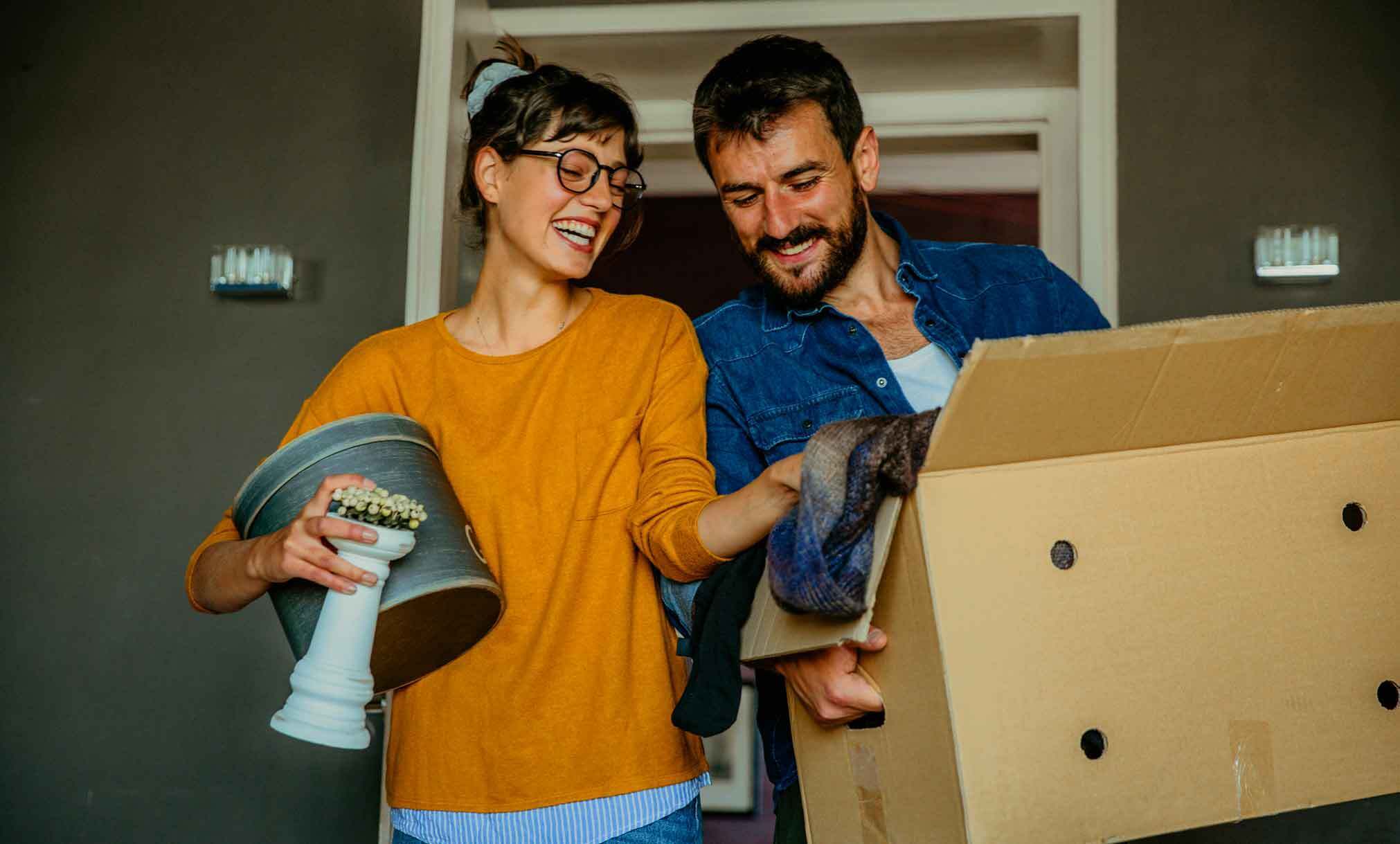 Couple moving into new flat carrying boxes